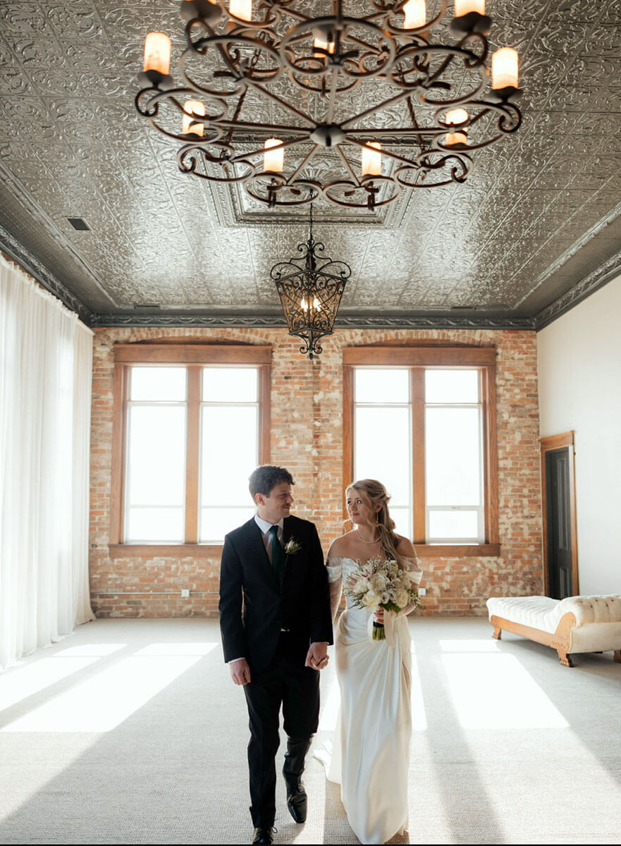 Bride and groom walking under chandeliers after the ceremony