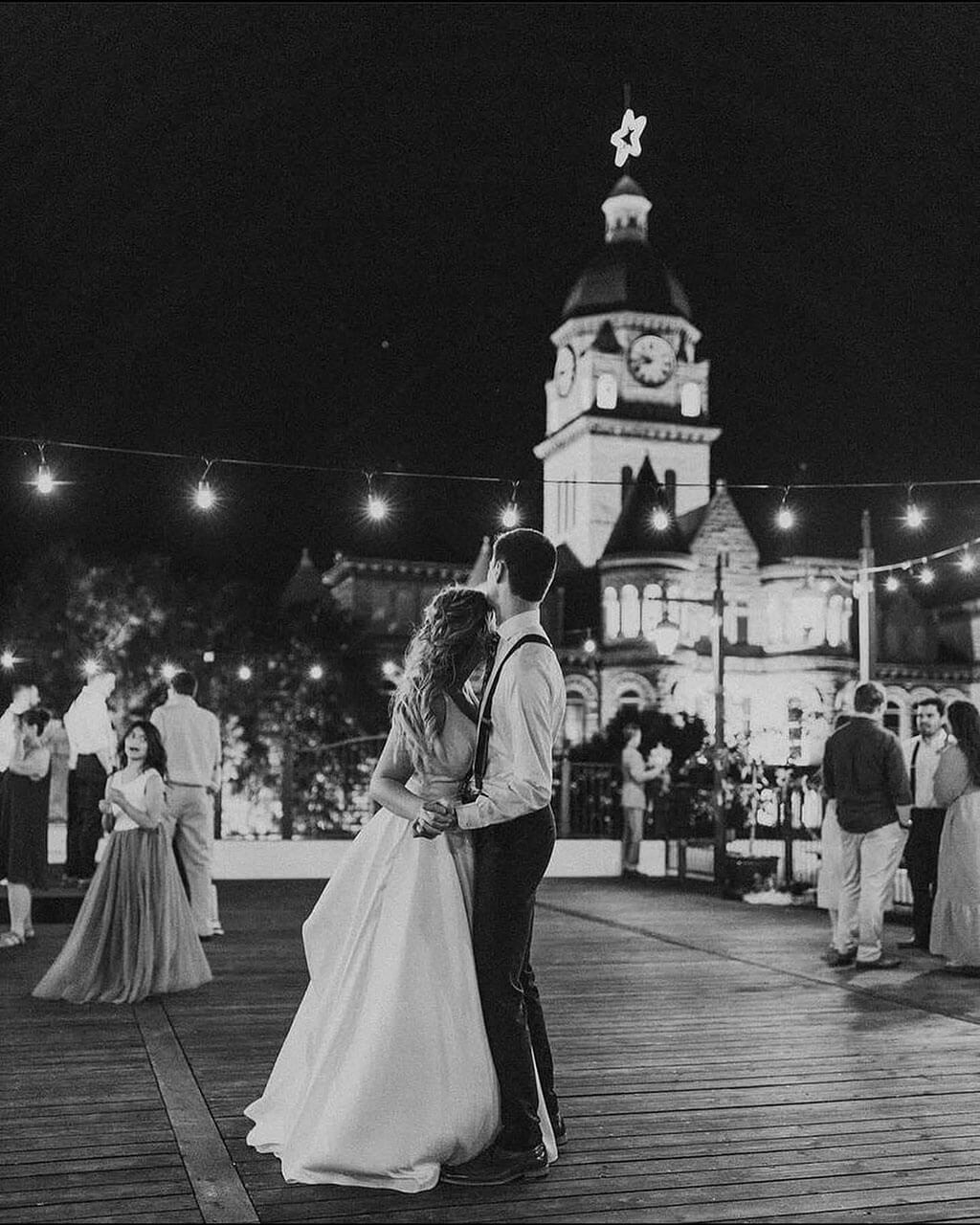 First dance on the rooftop at night under string lights with the courthouse lit up