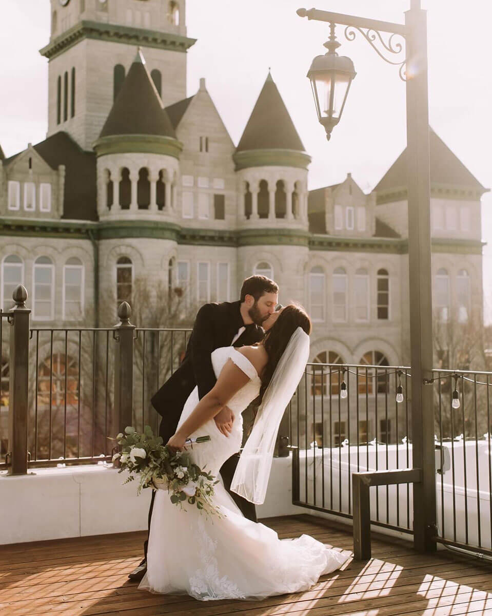 Groom dipping the bride on the rooftop with the courthouse in the background