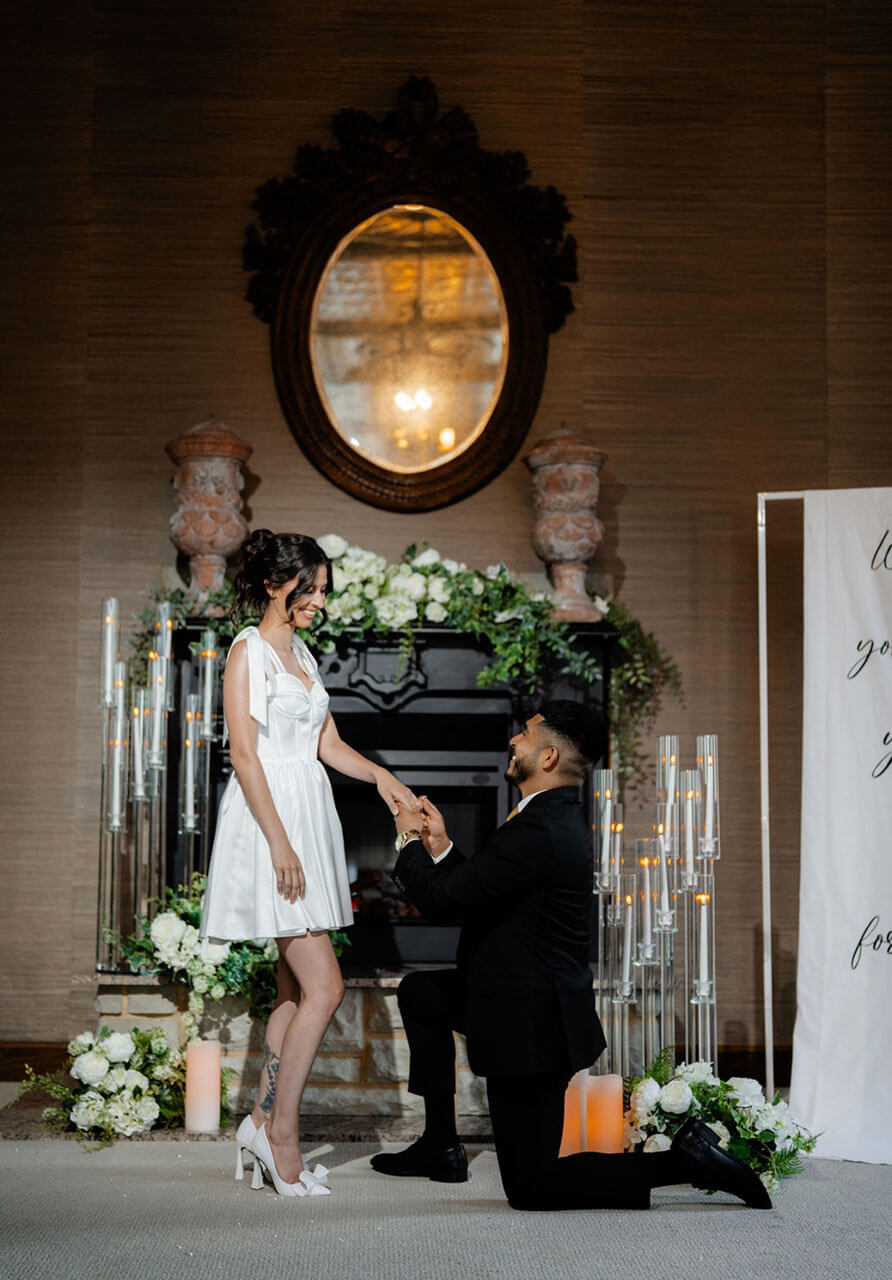 Bride and groom posed in the styled suite with a tufted chaise and fireplace