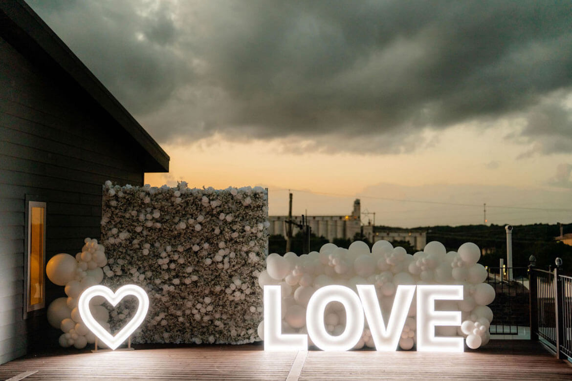 LOVE marquee letters and a floral wall on the rooftop at dusk